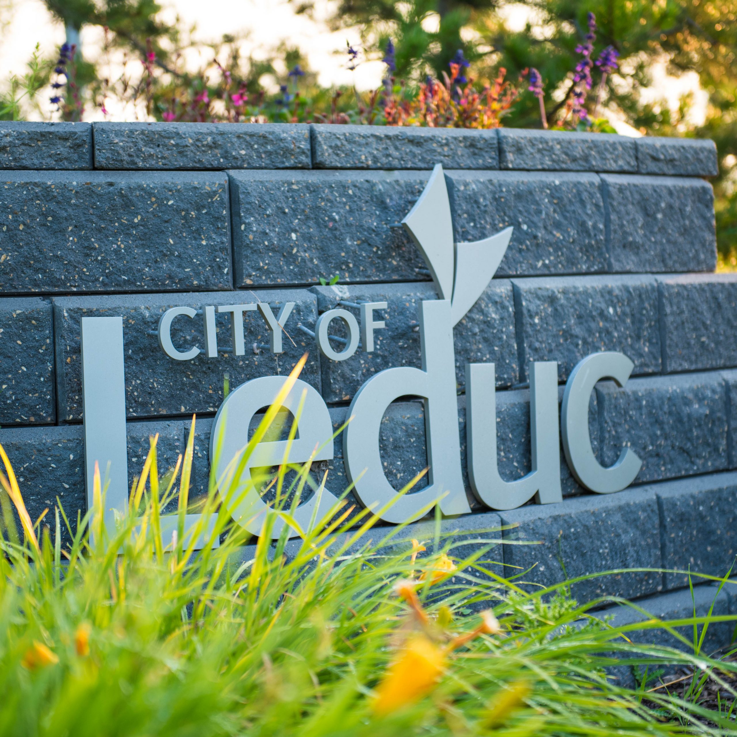 City of Leduc sign on stone wall with daylilies in the foreground